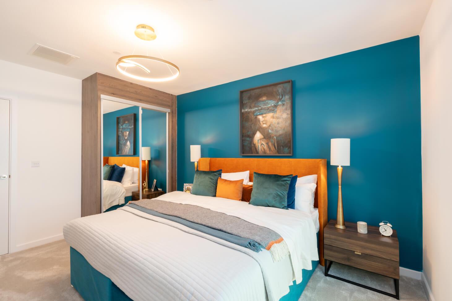 A bedroom in the Wembley Park Gardens Development, with blue walls and orange accents