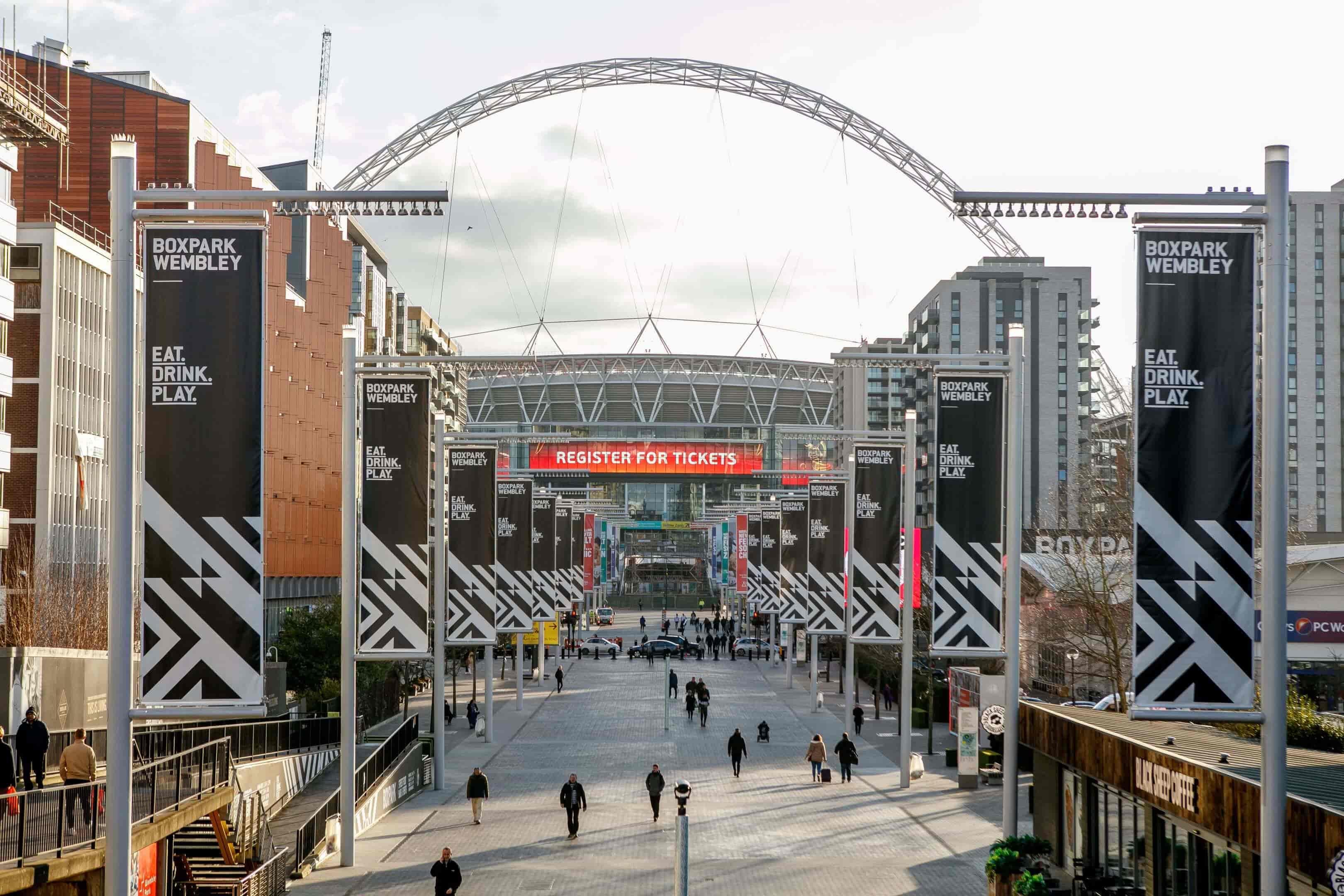 A city street in London adorned with a large number of banners, located near Wembley Park Gardens