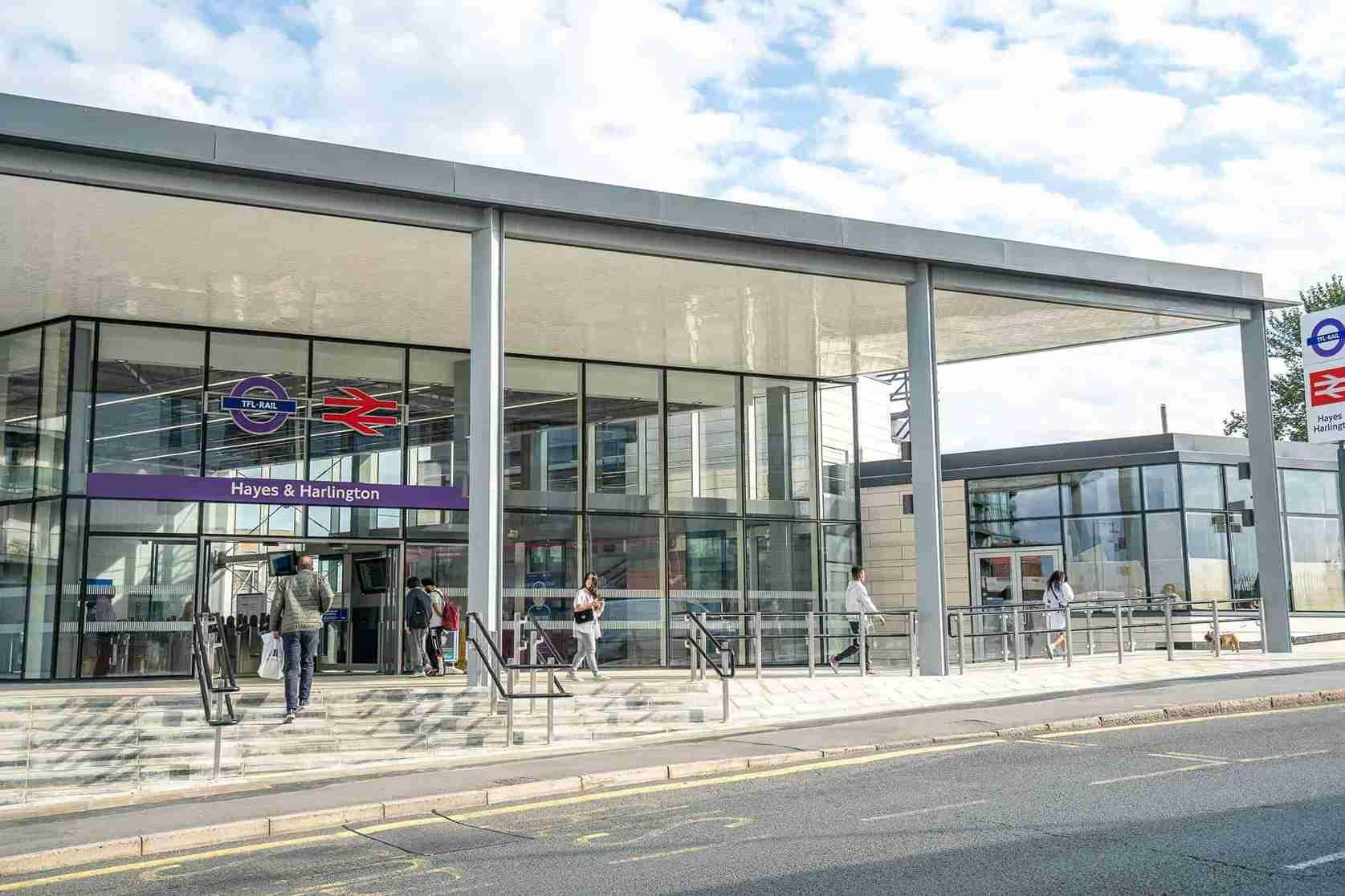 The entrance to Hayes Village Homes, a train station with people walking in front of it.