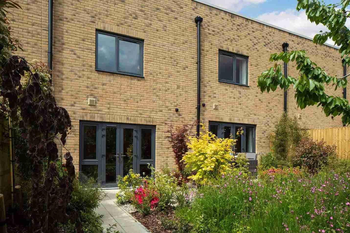 A brick house with a garden in front of it in the Springfield Place Development, SW17 7DJ, London