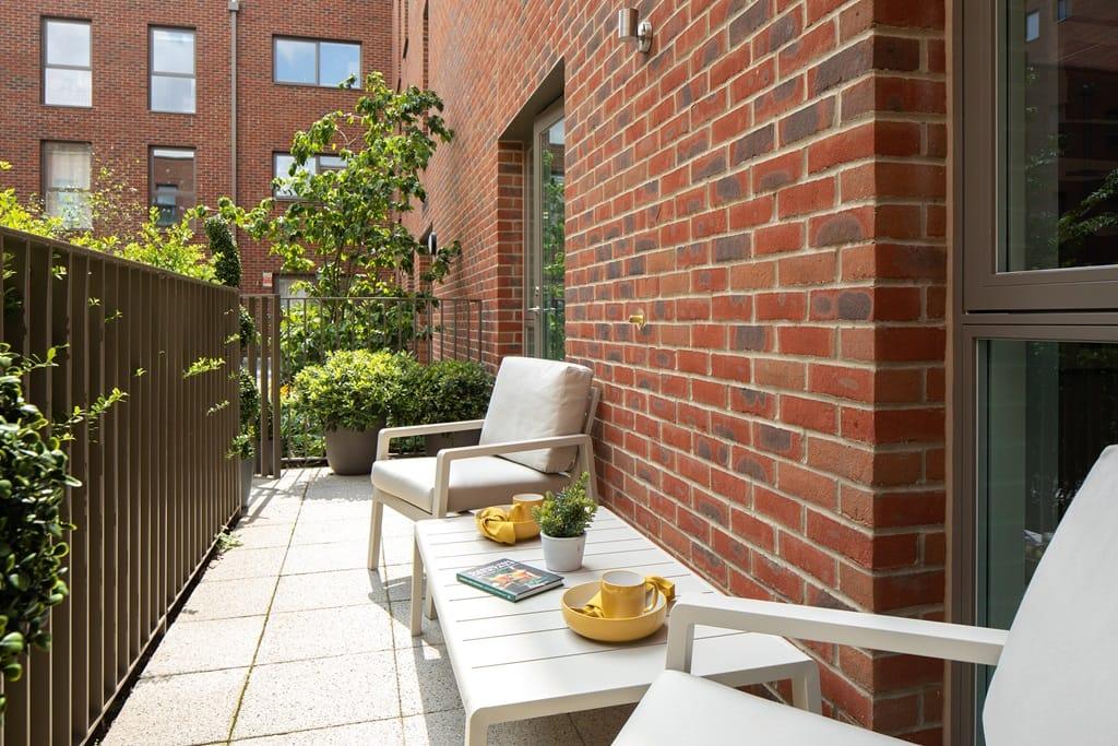 A balcony with a table and chairs in front of a brick wall at Eastman Village