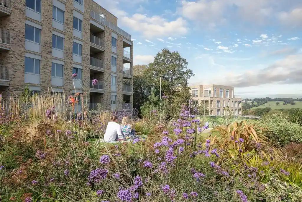 A woman sits on a bench in the garden of Ridgeway Views, an apartment building